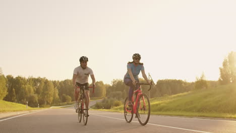 Steadicam-shot-of-mountain-biking-couple-riding-on-bike-trail-at-sunset-doing-high.